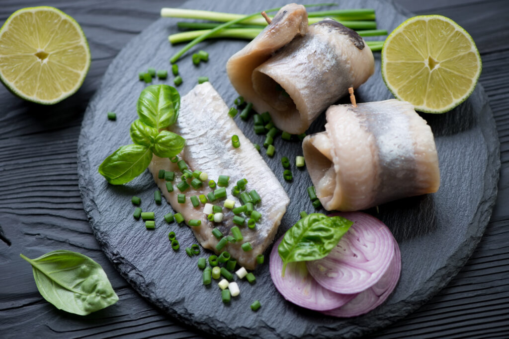 pickled herring topped with fresh herbs on a slate